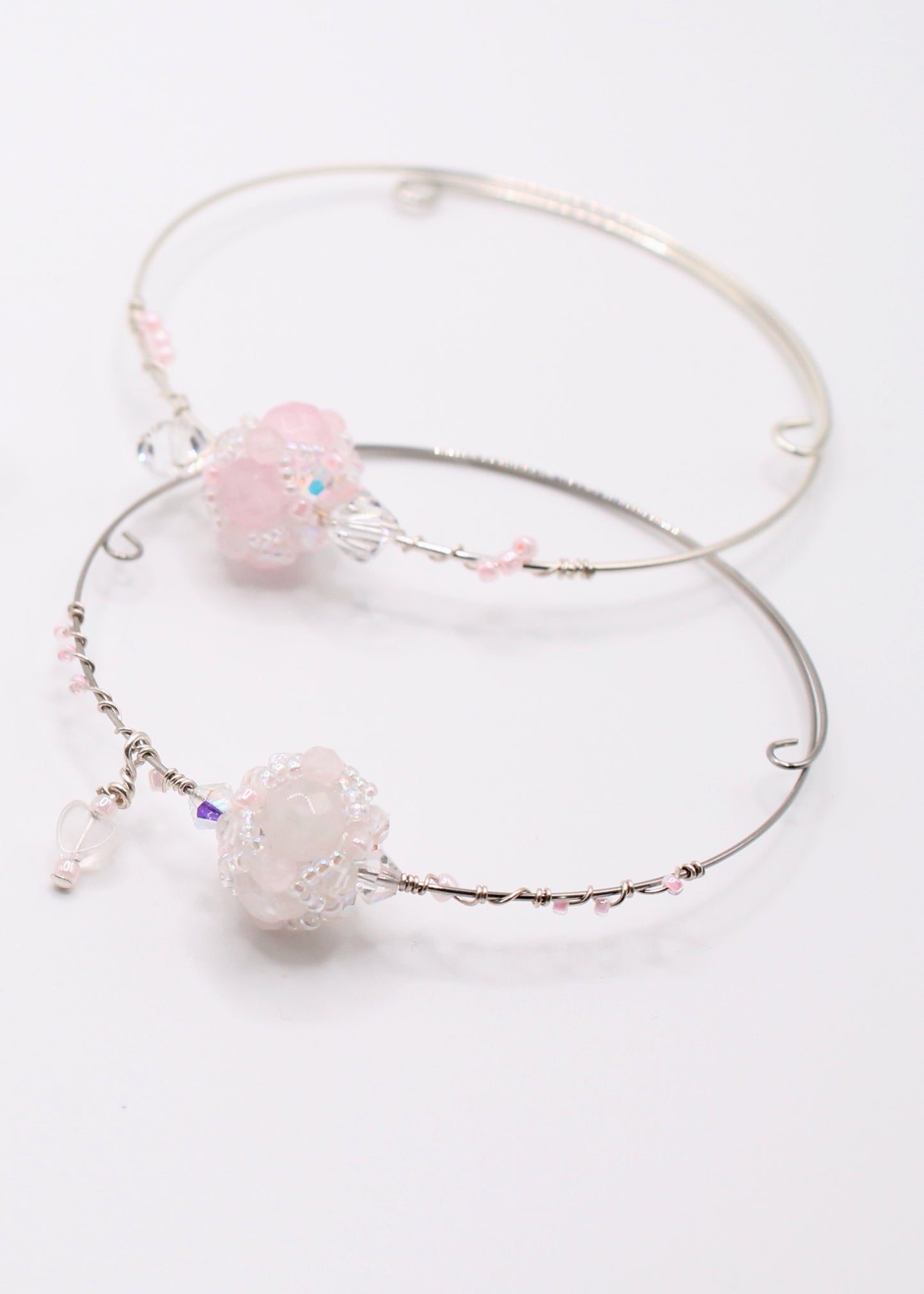 Hand sewn beaded pendant made with 72 glass, crystal, and rose quartz beads. The beaded pendant is placed on a bracelet and is adorned with wire wrapped beads in hues of pink, clear and white.